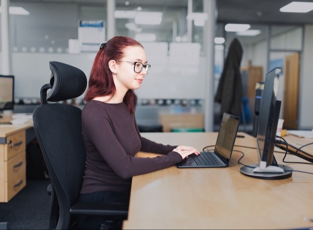 Woman typing on laptop in an office environment